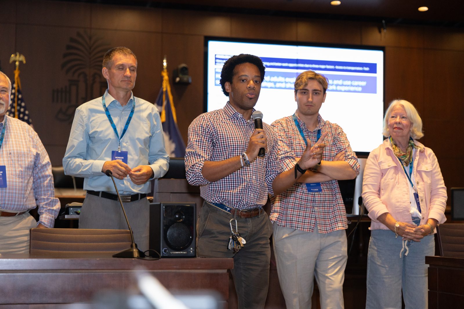 A delegate presents his working group's directive to the assembly, with group members standing beside him